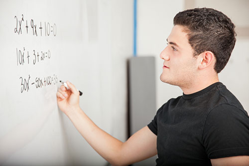 student writing algebraic expressions on a whiteboard