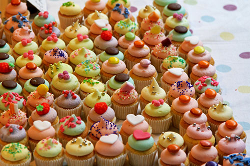 an assortment of dozens of decorated cupcakes