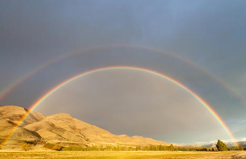 a double rainbow over a mountain range